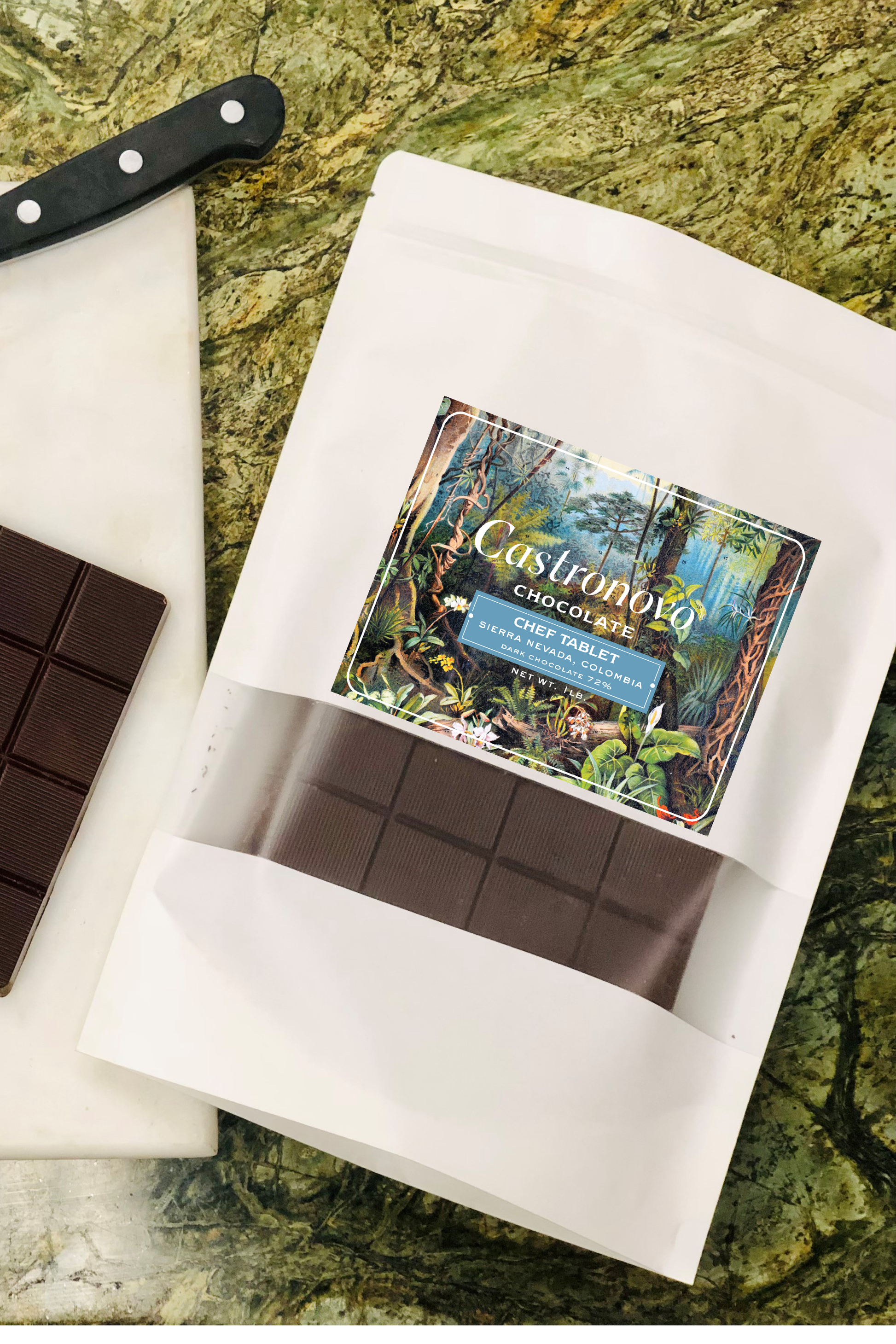 A chocolate chef tablet with a label showing the brand and possibly the Peruvian Amazonian landscape. The tablet is placed on a white paper, which is on a textured background.